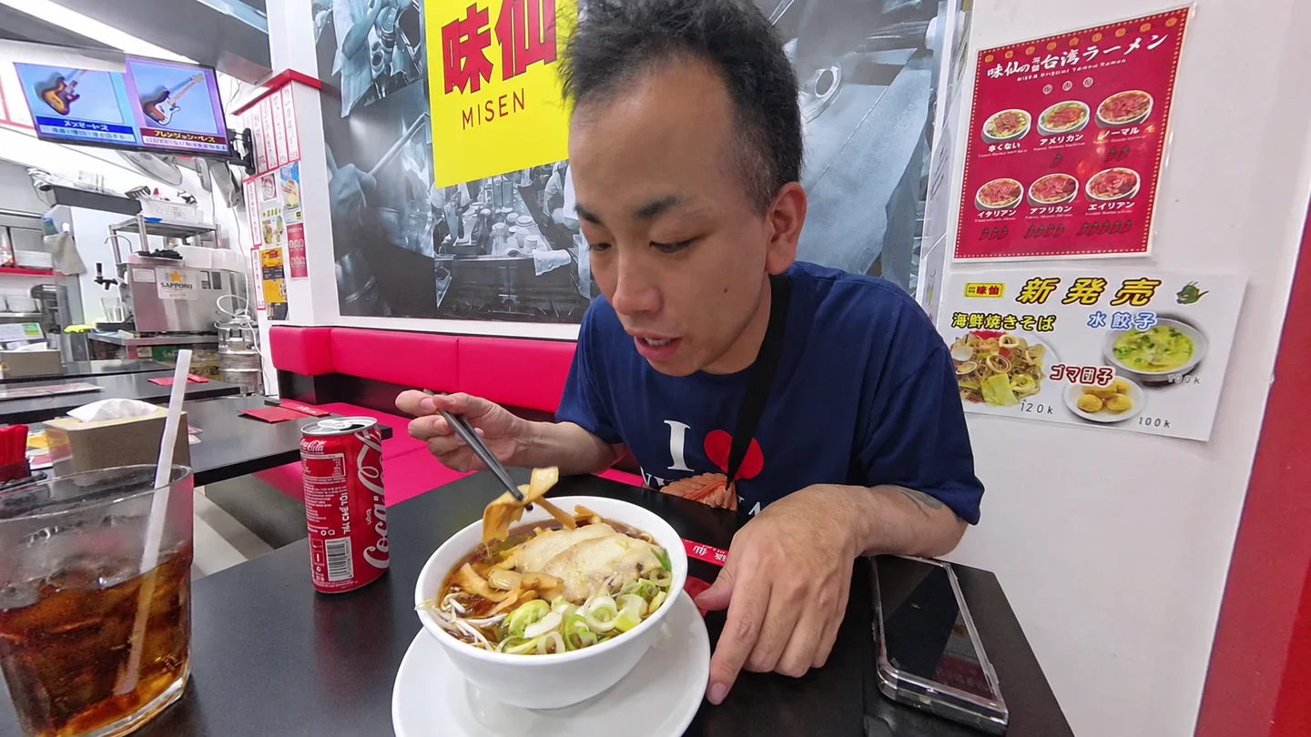 味仙の店内で醤油ラーメンを食べるTomo