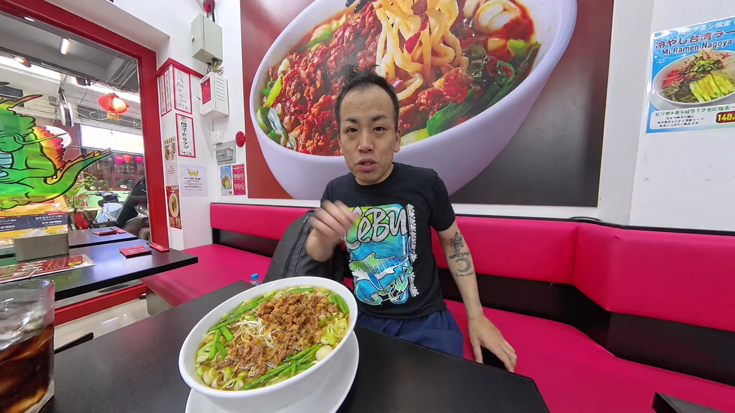 味仙で台湾ラーメンの丼をカメラに向けるTomo
