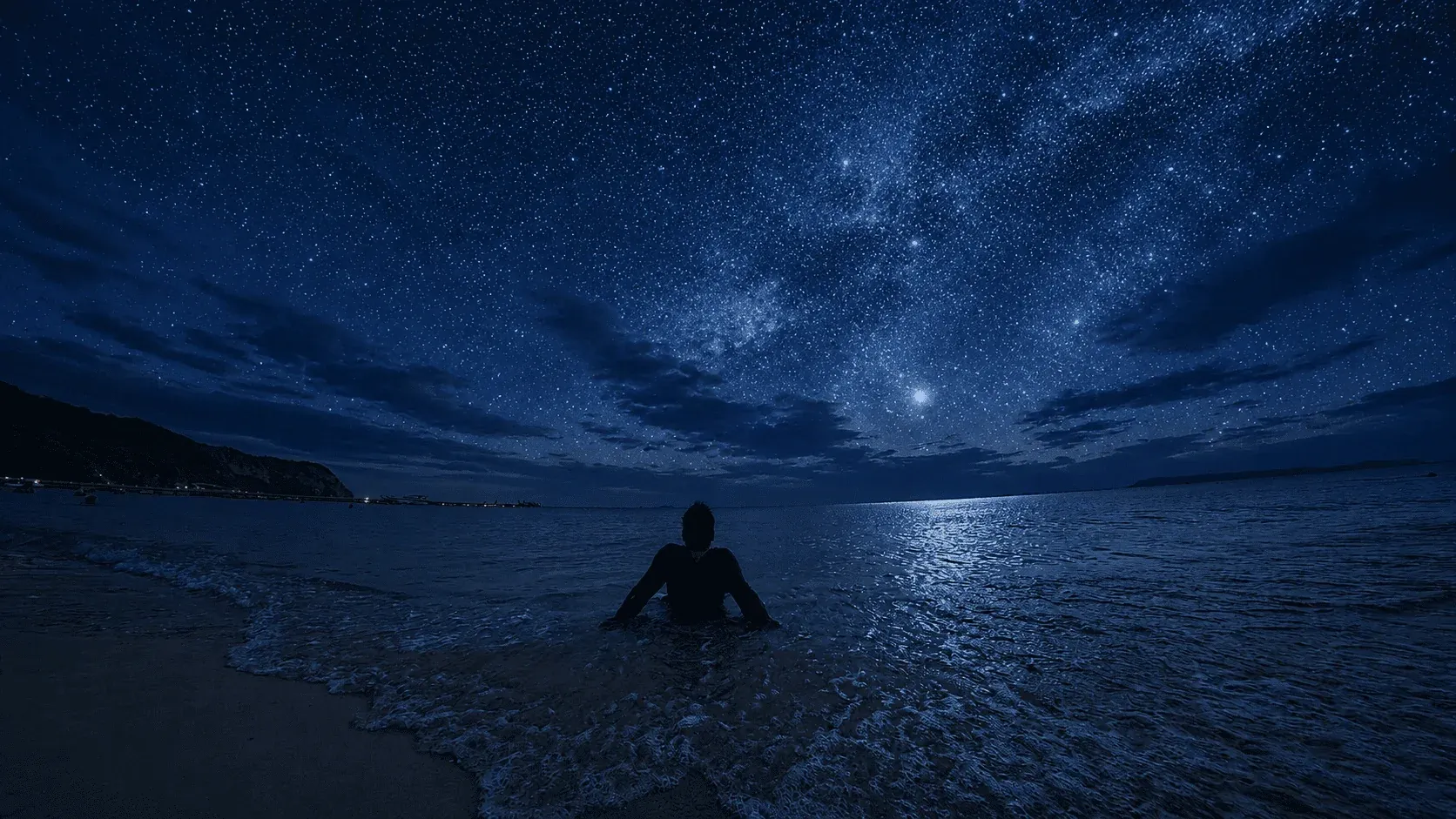 夜の海辺に立つ人物と星空。とも旅ちゃんねるのWebサイトでも使っている写真